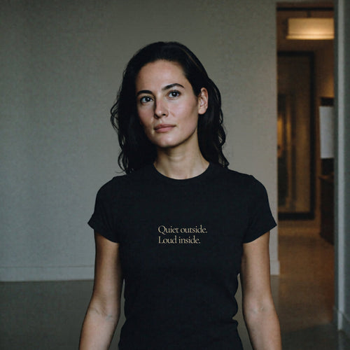 Woman wearing Question Everything Co. black t-shirt in hallway saying Quiet outside. Loud inside.