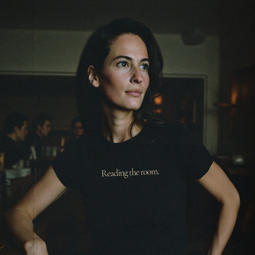 woman wearing question everything co. black tee reading the room