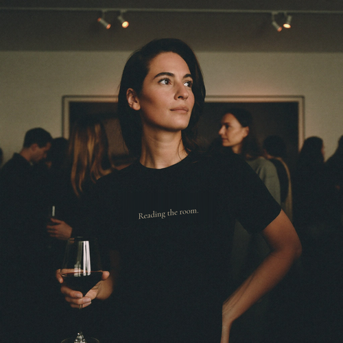 Person wearing a black Question Everything Co. tee that reads "Reading the room." — gallery opening